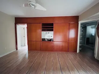 Interior de uma sala com painéis de madeira e piso de tábuas.