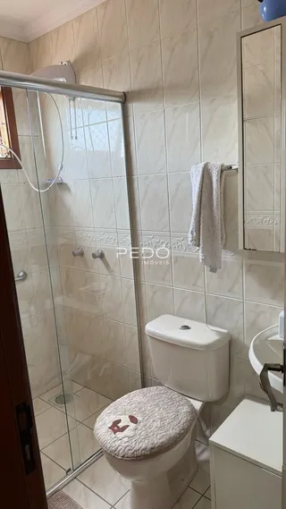 Um banheiro com revestimento de azulejos claros e box de vidro.