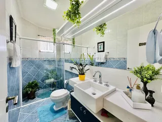 Foto de um banheiro com azulejos azuis e brancos e box de chuveiro de vidro.