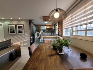 Ambiente interno de uma sala de estar com piso de madeira e grande janela.
