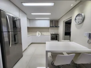 Imagem de uma cozinha moderna com armários brancos e eletrodomésticos de aço inoxidável.
