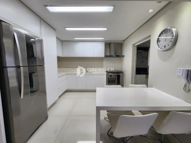 Imagem de uma cozinha moderna com armários brancos e eletrodomésticos de aço inoxidável.