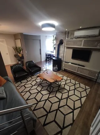 Sala de estar com sofá de couro e piso de madeira em um imóvel no Brasil.