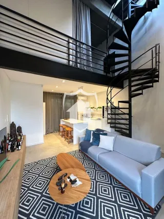 Sala de estar com sofá e escadaria em um apartamento.
