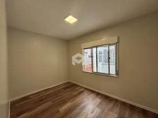 Ambiente interno de uma sala com piso de madeira e janela.