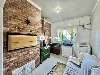Cozinha com parede de tijolo aparente e armários verdes.