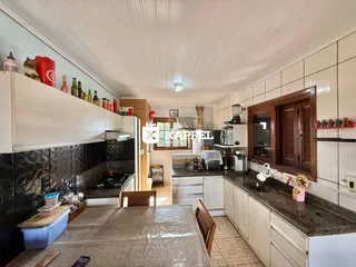 Foto interna de uma cozinha com armários brancos e bancadas escuras.