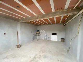 Foto de um cômodo interno em fase de obra com teto de madeira exposto.