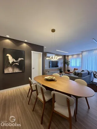 Uma sala de jantar com mesa de madeira e cadeiras em um imóvel.