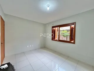 Ambiente interno de uma sala com piso de cerâmica e janela de madeira.