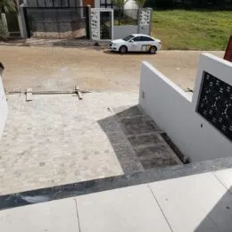 Área externa pavimentada com lajes claras em uma propriedade.