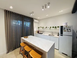 Vista da cozinha moderna com bancada de mármore e armários brancos.