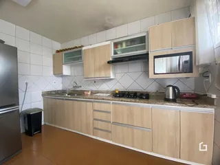 Cozinha com armários de madeira clara e revestimento de azulejos brancos.