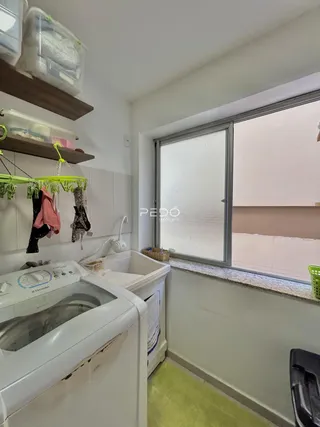 Interior de uma área de serviço com máquina de lavar roupa e janela de porta.