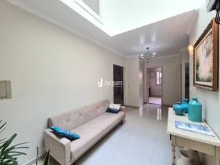 Sala de estar com sofá claro e paredes brancas em um imóvel no Brasil.