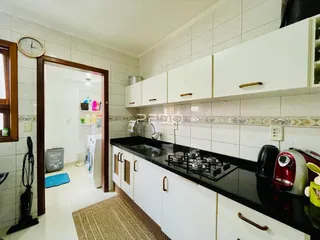 Cozinha com armários brancos e bancada preta em imóvel no Brasil.