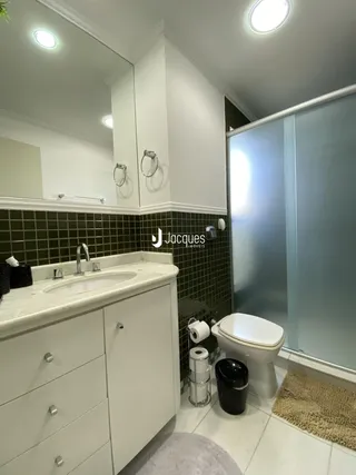 Banheiro com revestimento de azulejos e bancada de mármore.