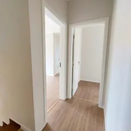 Hall de passagem com piso de madeira clara.