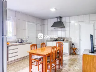Cozinha com bancada e mesa de jantar de madeira.