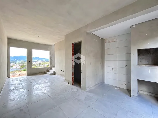 Interior de uma sala ampla com janelas que dão vista para a paisagem.