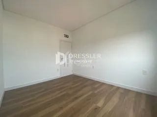 Foto de um cômodo interno com piso de madeira clara e paredes brancas.