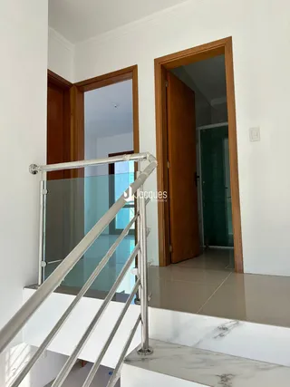 Uma escadaria com corrimão de vidro e portas de madeira em um ambiente interno.