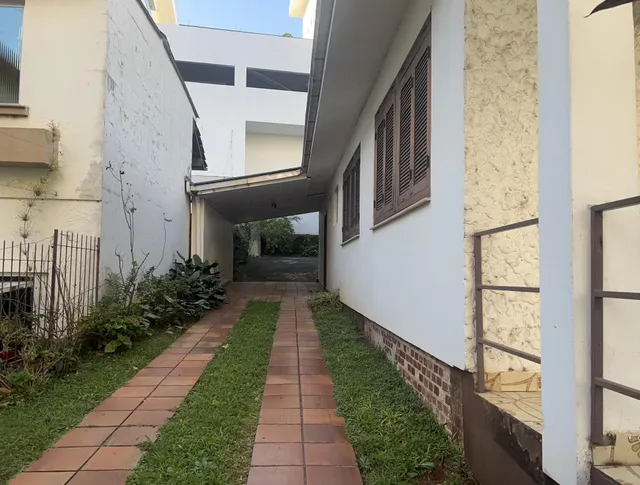 Vista de um corredor externo pavimentado com tijolos e grama.