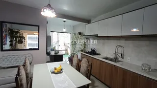 Interior de uma sala de estar com cozinha e mesa de jantar em um imóvel no Brasil.