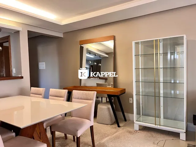 Sala de jantar com mesa de madeira e cadeiras estofadas em um ambiente claro.