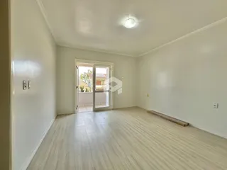 Ambiente interno de uma sala com piso de madeira clara e paredes brancas.