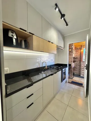 Cozinha moderna com armários brancos e bancadas escuras.