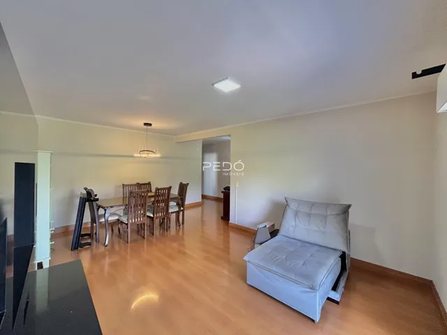 Sala de estar com piso de madeira e mesa de jantar.