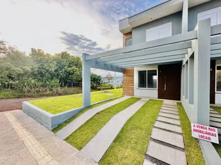 Fachada de uma residência moderna em Lajeado, Brasil, com jardim gramado e área coberta.