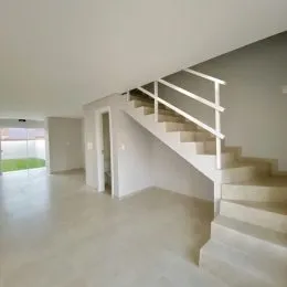 Hall de entrada com escadaria em um ambiente claro.
