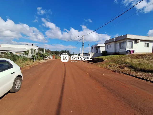 Vista da rua de terra em frente a uma residência branca.