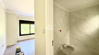 Vista de um corredor com um banheiro de paredes brancas e mármore claro.