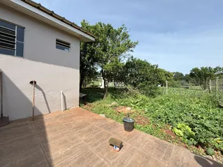 Vista da fachada de uma casa com pátio e jardim ao fundo.