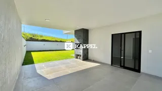 Vista de um pátio externo com gramado e parede branca.