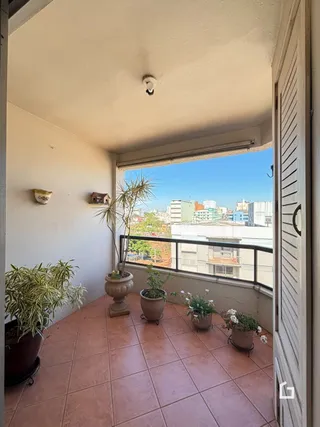 Vista da varanda com piso de cerâmica e vasos de plantas.
