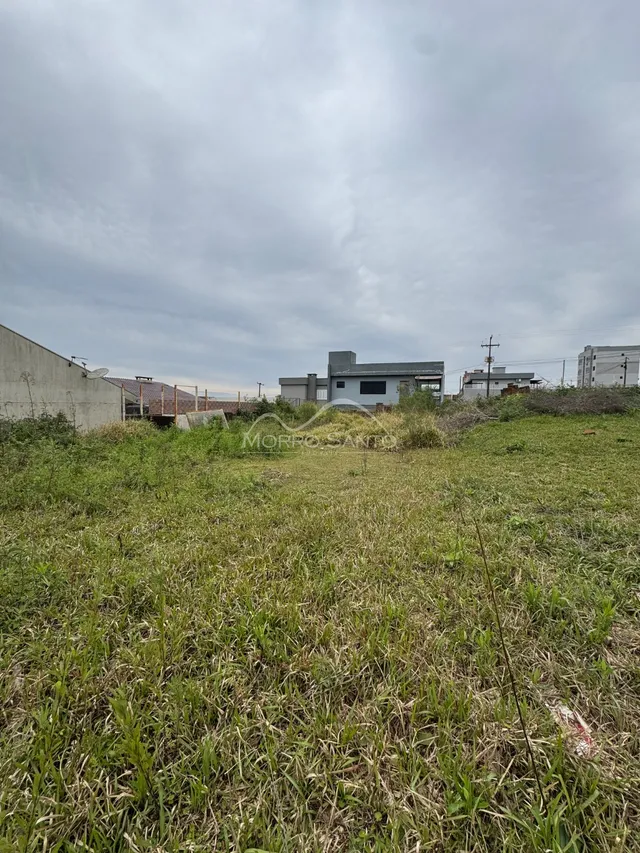Vista externa da propriedade mostrando um terreno com grama alta sob um céu nublado.