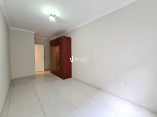 Interior de uma sala com piso de cerâmica clara e paredes brancas.