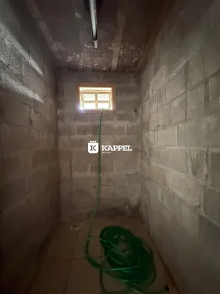 Corredor interno com paredes de concreto aparente e piso de cerâmica.