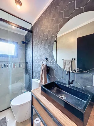 Foto de um banheiro moderno com box de vidro e pia escura.