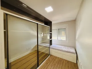 Quarto com piso de madeira e divisória de vidro.