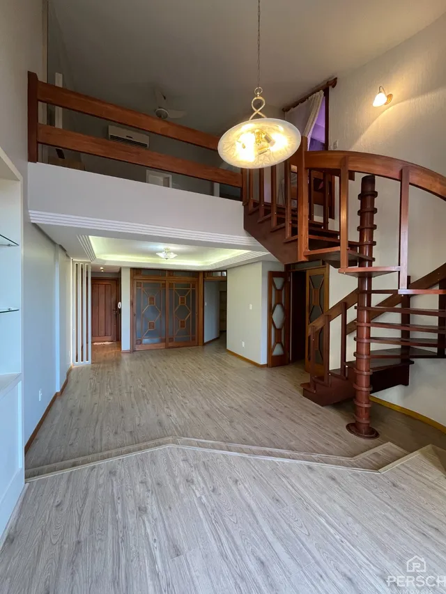 Hall de entrada com escadaria de madeira e piso de madeira clara.
