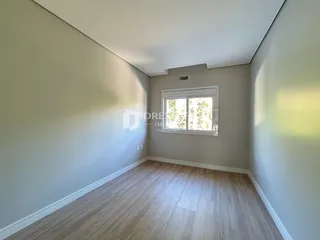 Ambiente interno de uma sala com piso de madeira clara e paredes brancas.