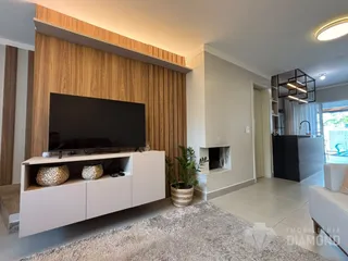 Sala de estar moderna com painel de madeira e televisão.