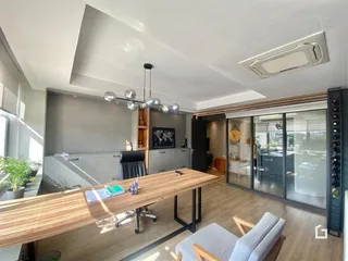 Interior de uma sala de estar moderna com piso de madeira e grande abertura para o exterior.