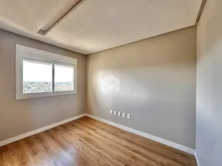 Interior de uma sala com piso de madeira e janela voltada para a paisagem.