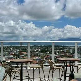 Varanda com mesas e cadeiras com vista para o mar.